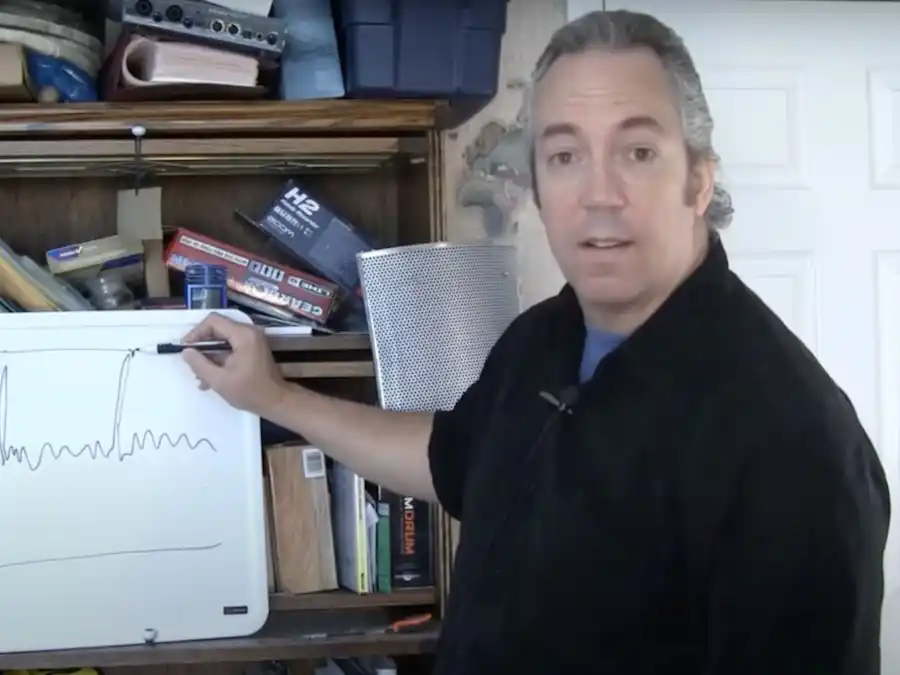 Ken Theriot stands beside a whiteboard in a workshop, pointing at a hand-drawn audio waveform graph while explaining a concept.